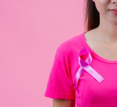 Breast cancer awareness month, Woman in pink t-shirt with satin pink ribbon on her chest, supporting symbol of breast cancer awareness campaign in October.